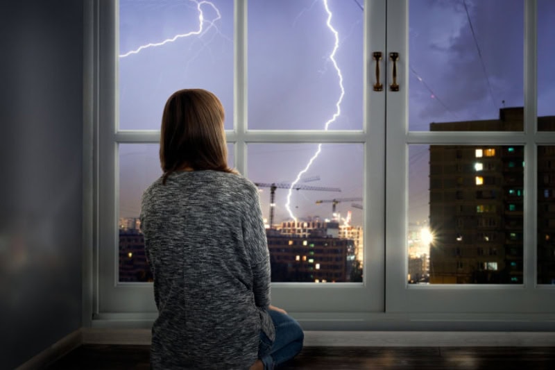 How to Protect Your AC From Storms - girl gazing at storm.